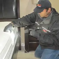 Bed bug inspection technician checking a mattress and bed frame for signs of infestation in Chattanooga, TN