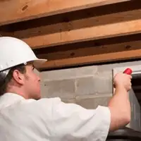 Termite inspection technician checking a basement wall and framing for termite activity in Chattanooga, TN